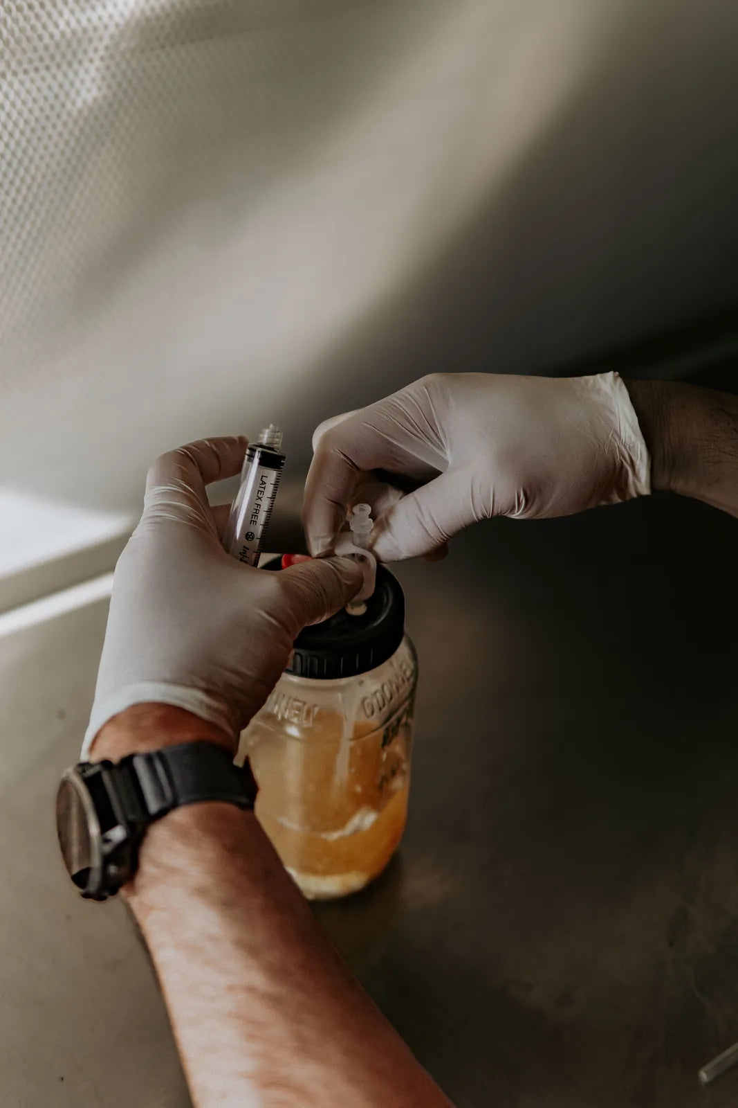 Gloved hand setting the syringe to the jar's injection port